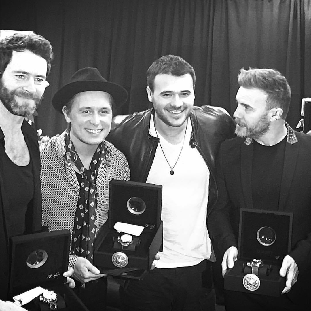 Four men holding award plaques backstage
